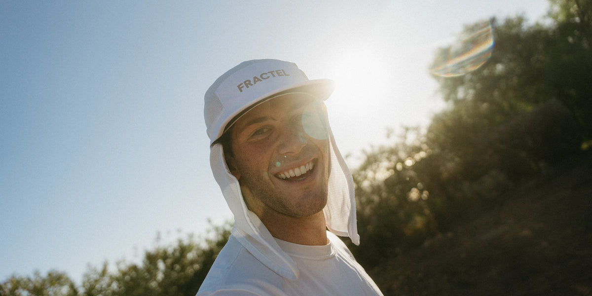 Smiling runner in a white Fractel premium legionnaire running hat with a neck cape in low sun