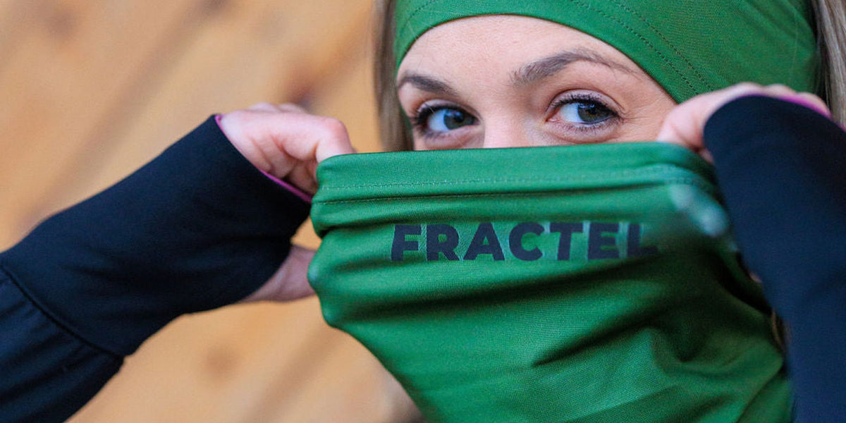 Runner pulling up a green Fractel neck gaiter from our neck gaiters range, with a matching green headband