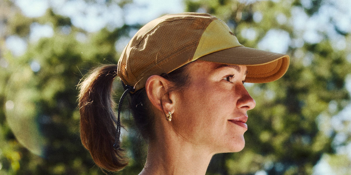 Woman in profile wearing a tan Fractel cap with her ponytail through the back, hats for small heads