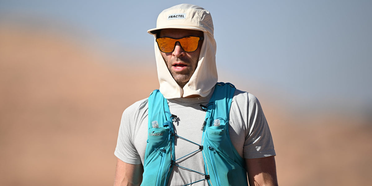 Runner in a cream Fractel core legionnaire running hat with a neck flap, orange sunglasses and a teal running vest