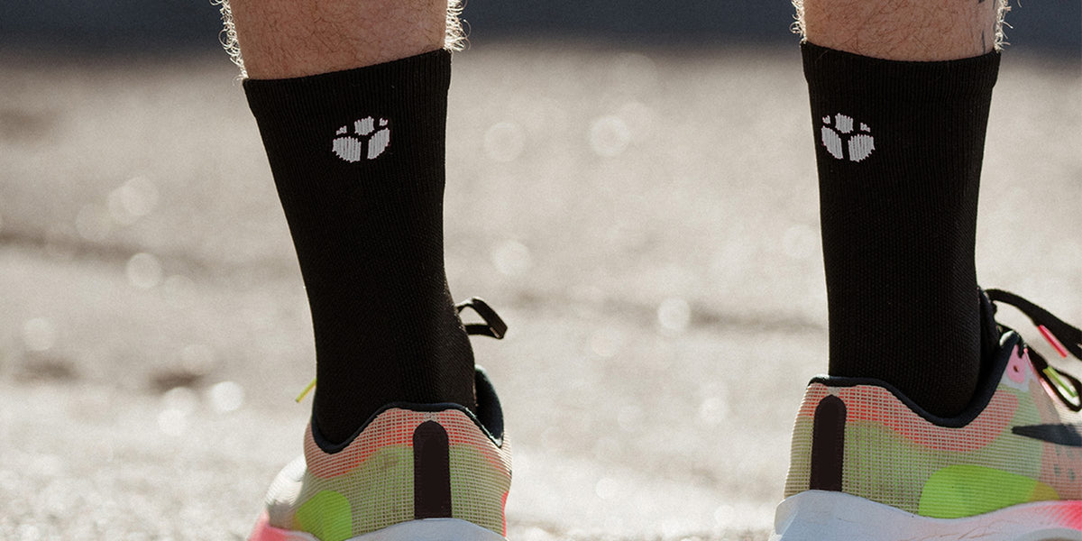 Black Fractel performance running socks with a white logo, worn with bright running shoes