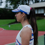 Woman wearing a white cap with blue and red accents on a track