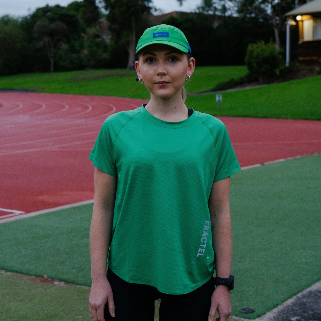 Female wearing a green shirt and cap on a track