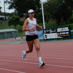 Woman running on a track in white performance singlet