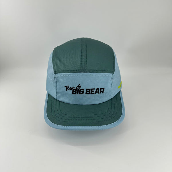 A light blue and dark teal 5-panel cap with 'Tour de BIG BEAR' embroidered on the front, displayed on a neutral light gray background.