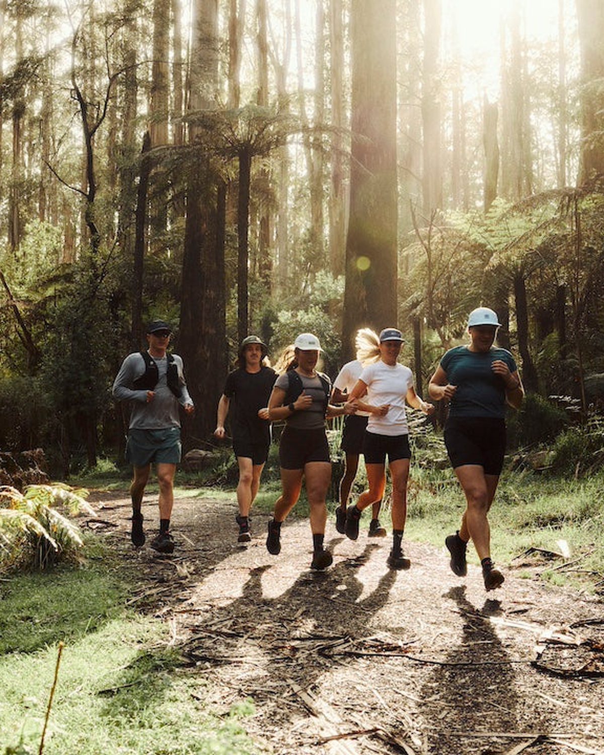 Trail running hats worn by Fractel runners in a tall forest