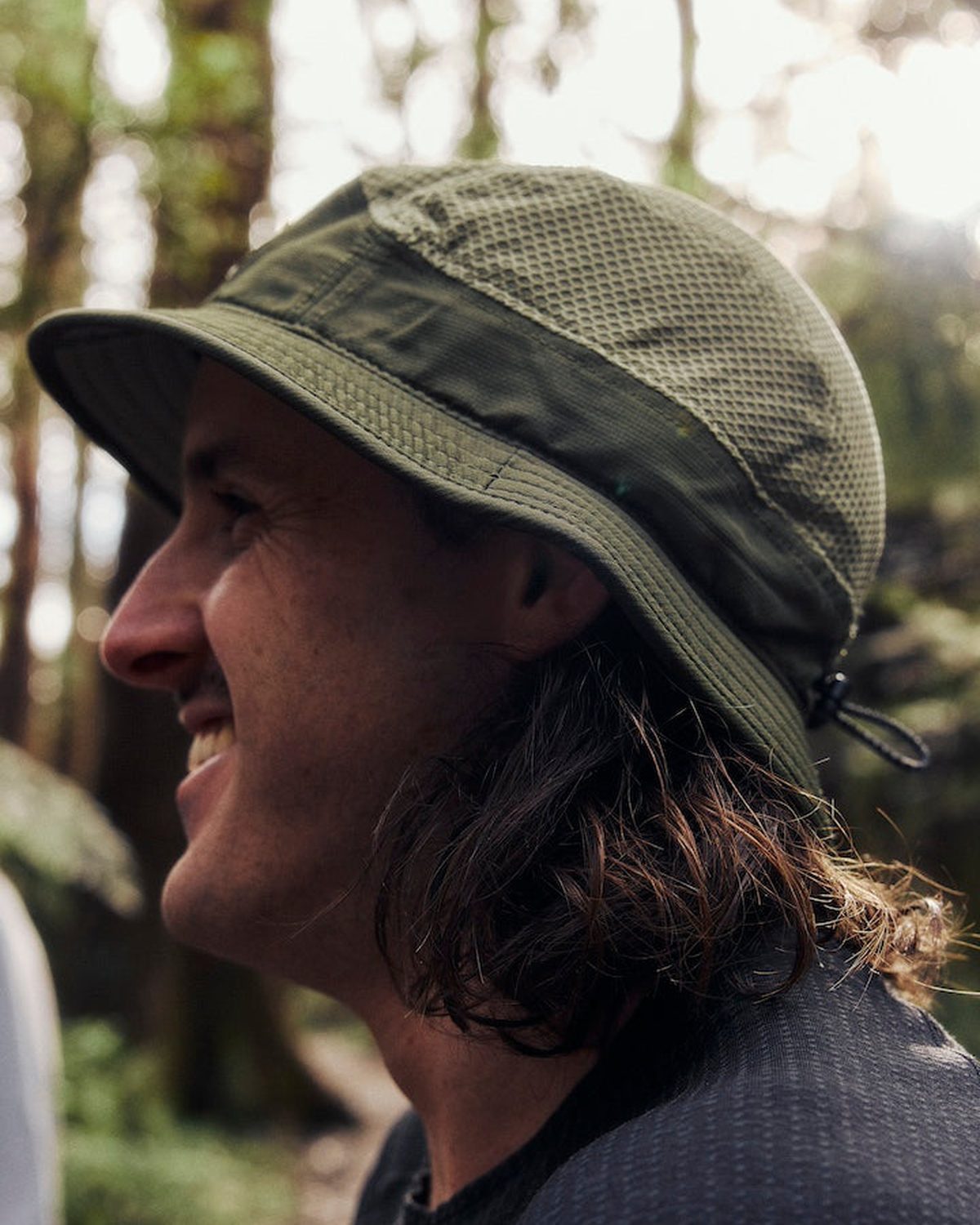 Premium bucket hat in olive worn by a smiling trail runner