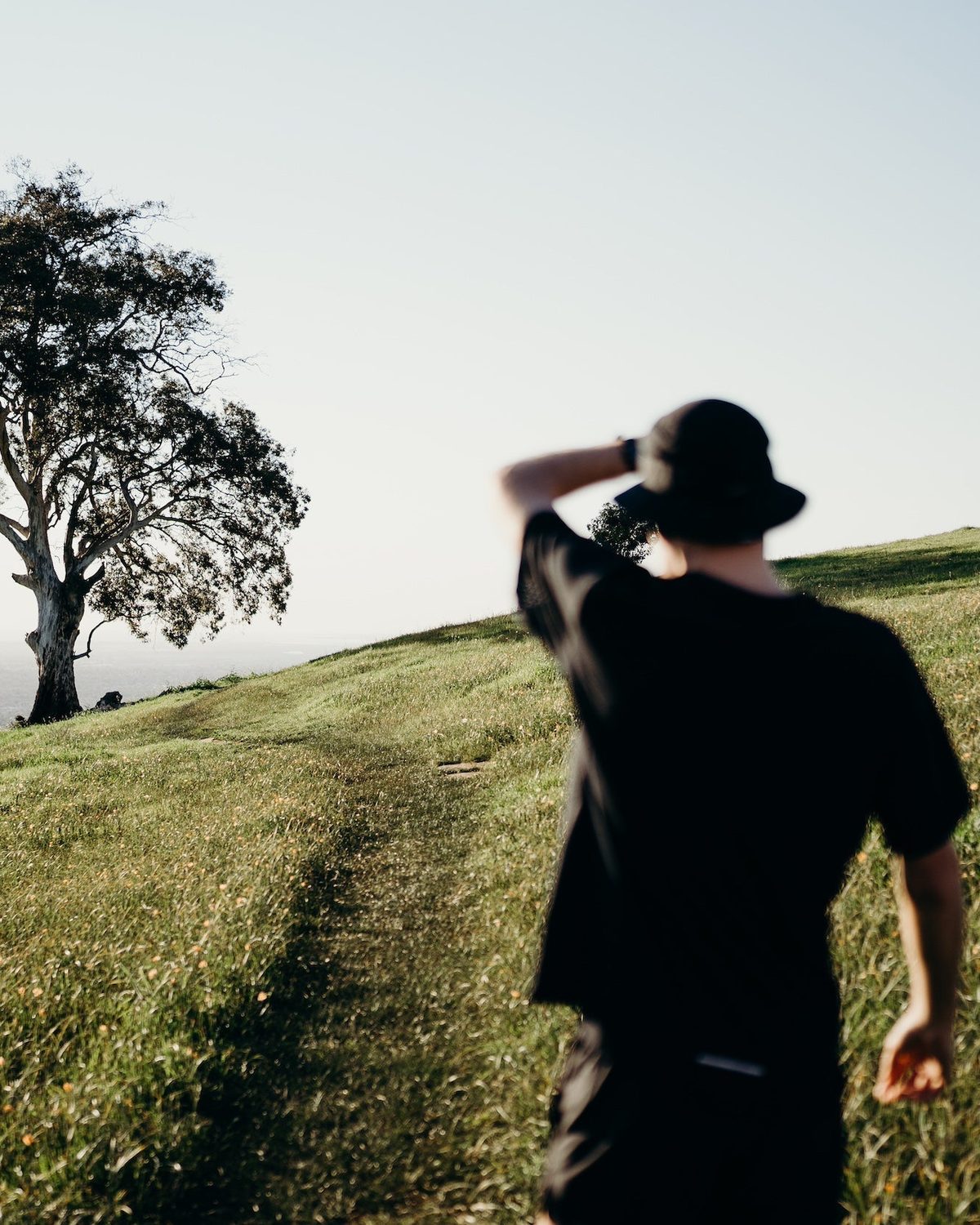 Seasonal bucket hat in black worn by a runner on a grassy hillside