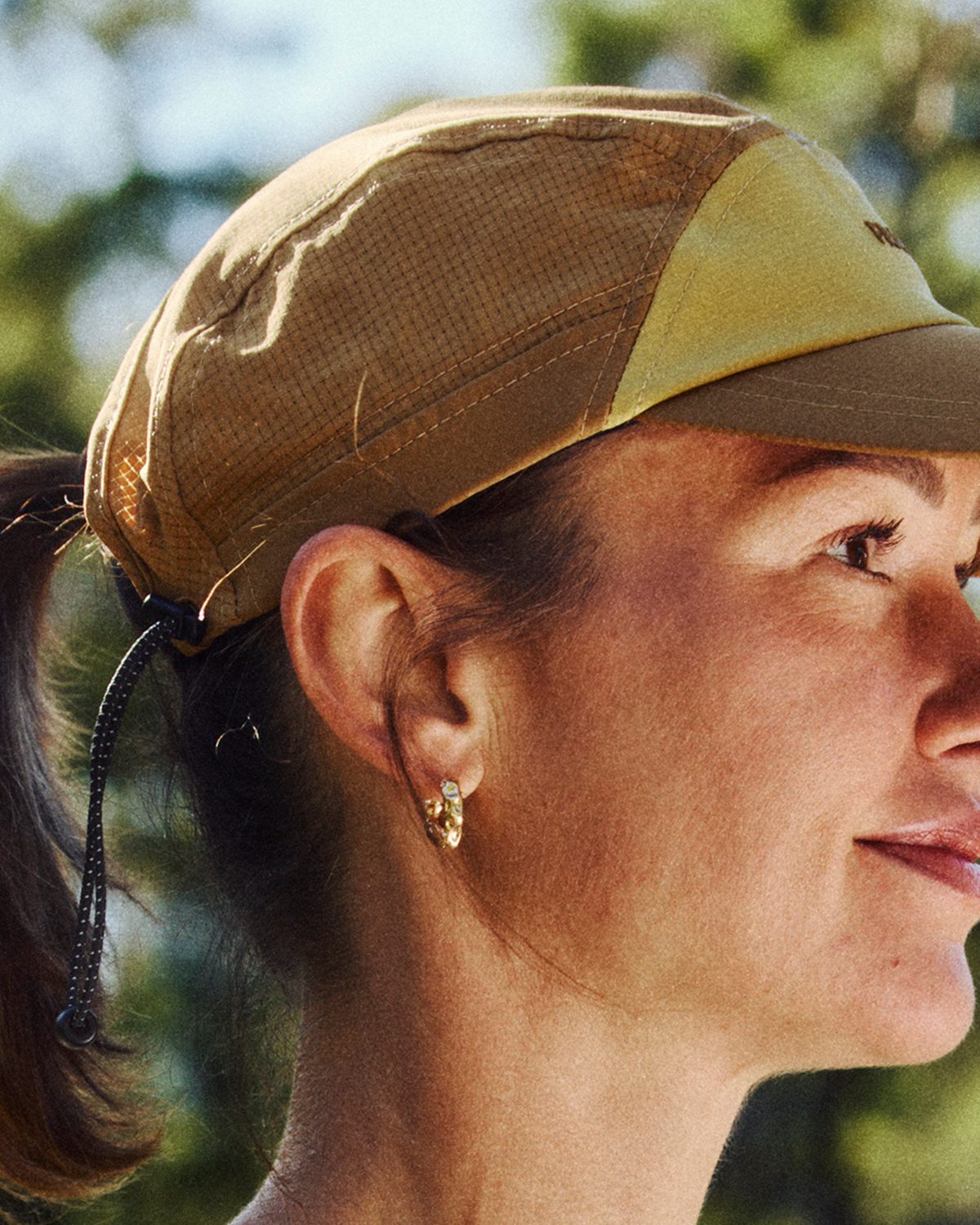 Running cap for small heads in tan worn with a high ponytail