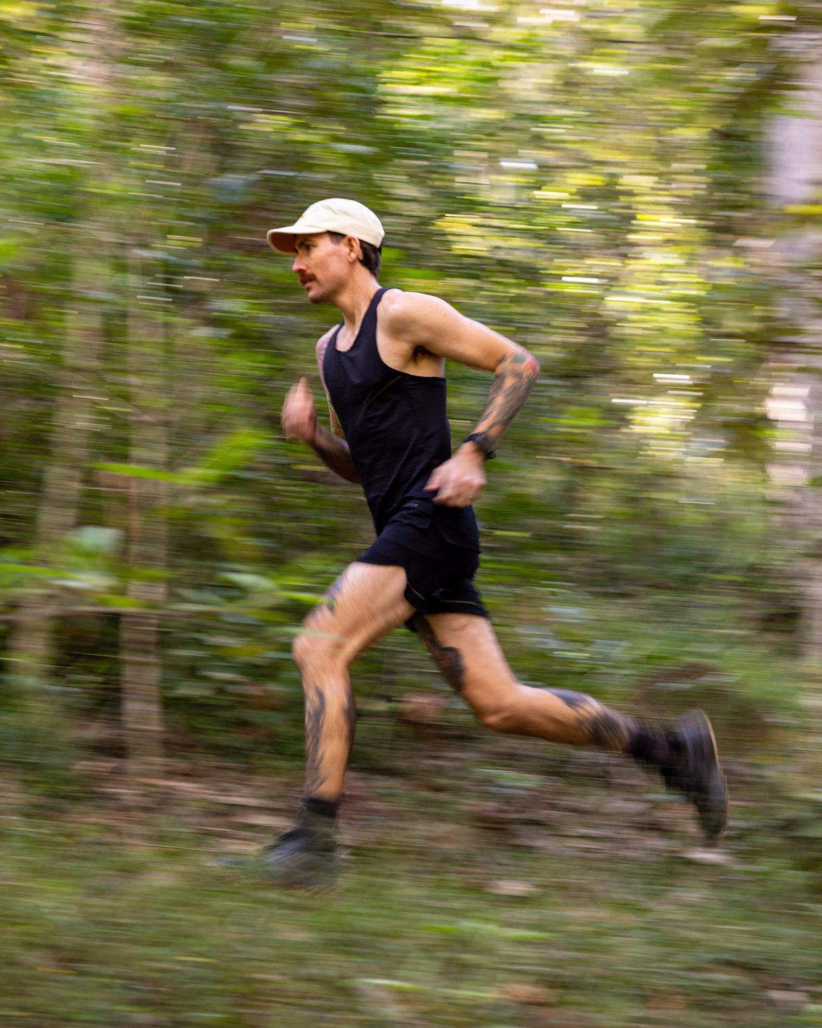 Fractel Core collection runner in a black singlet in a blur of forest green