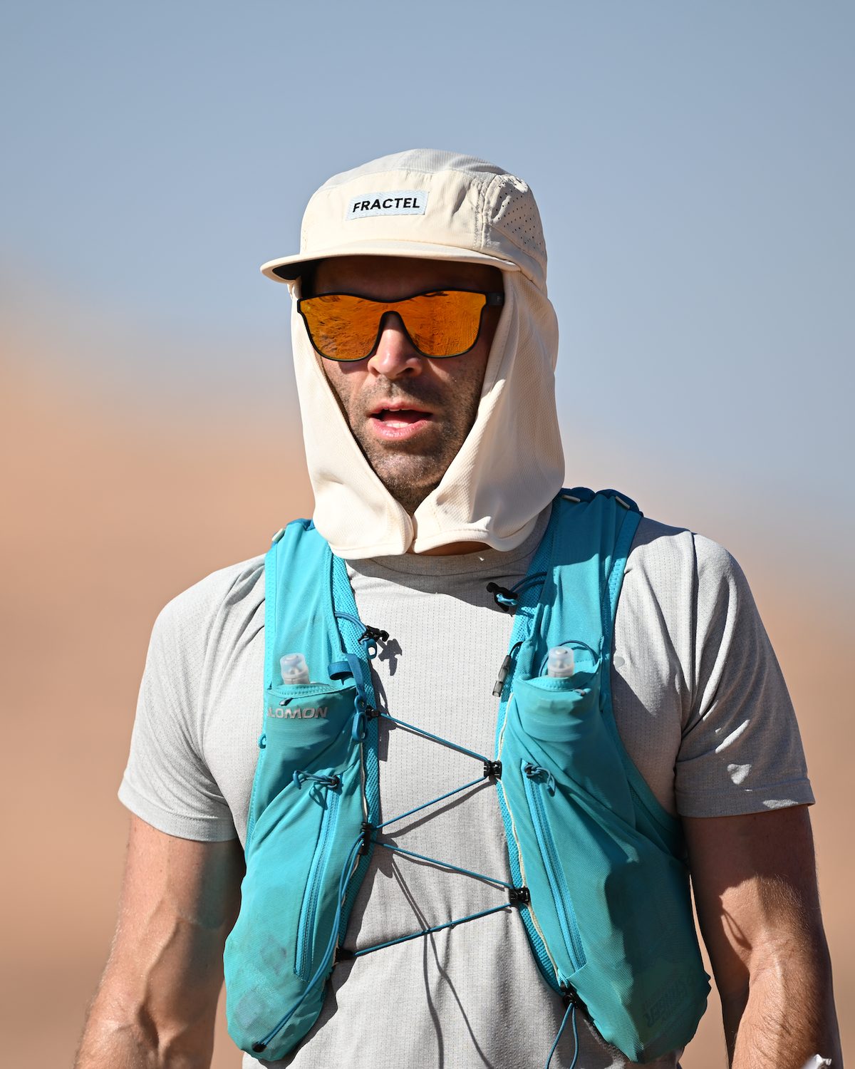 Core legionnaire running hat with a neck flap worn against a warm orange backdrop