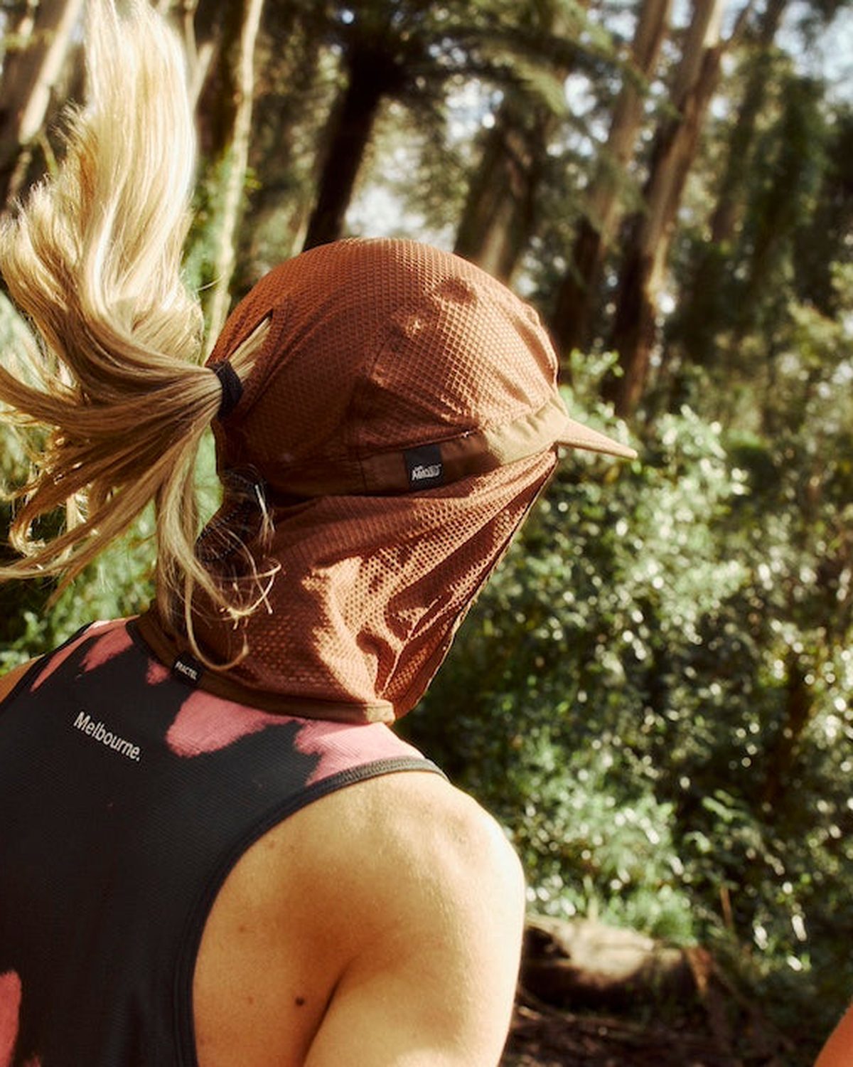 Seasonal legionnaire running hat in rust worn on a forest trail