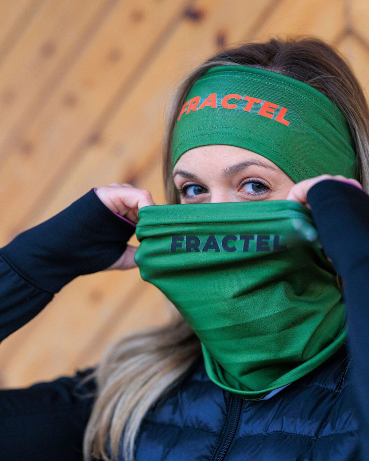 Green Fractel neck gaiter with the logo pulled up over the nose