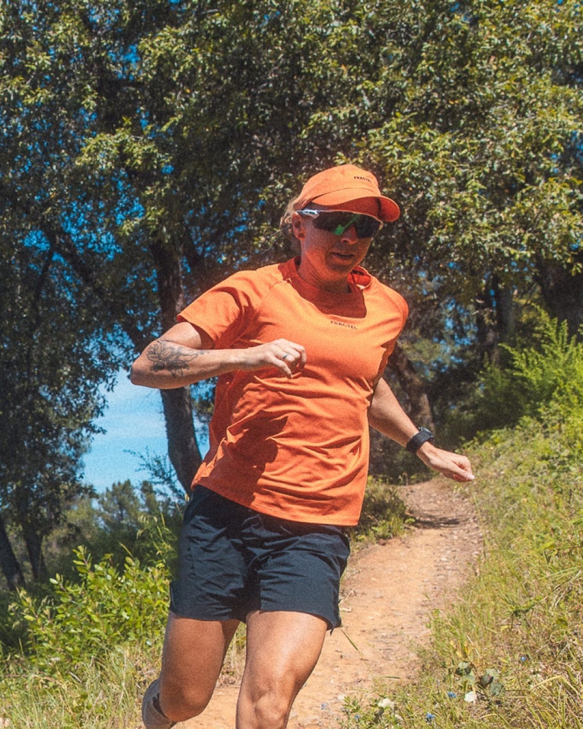 Fractel Sierra Nevada collection: runner in an orange tee and cap on a trail