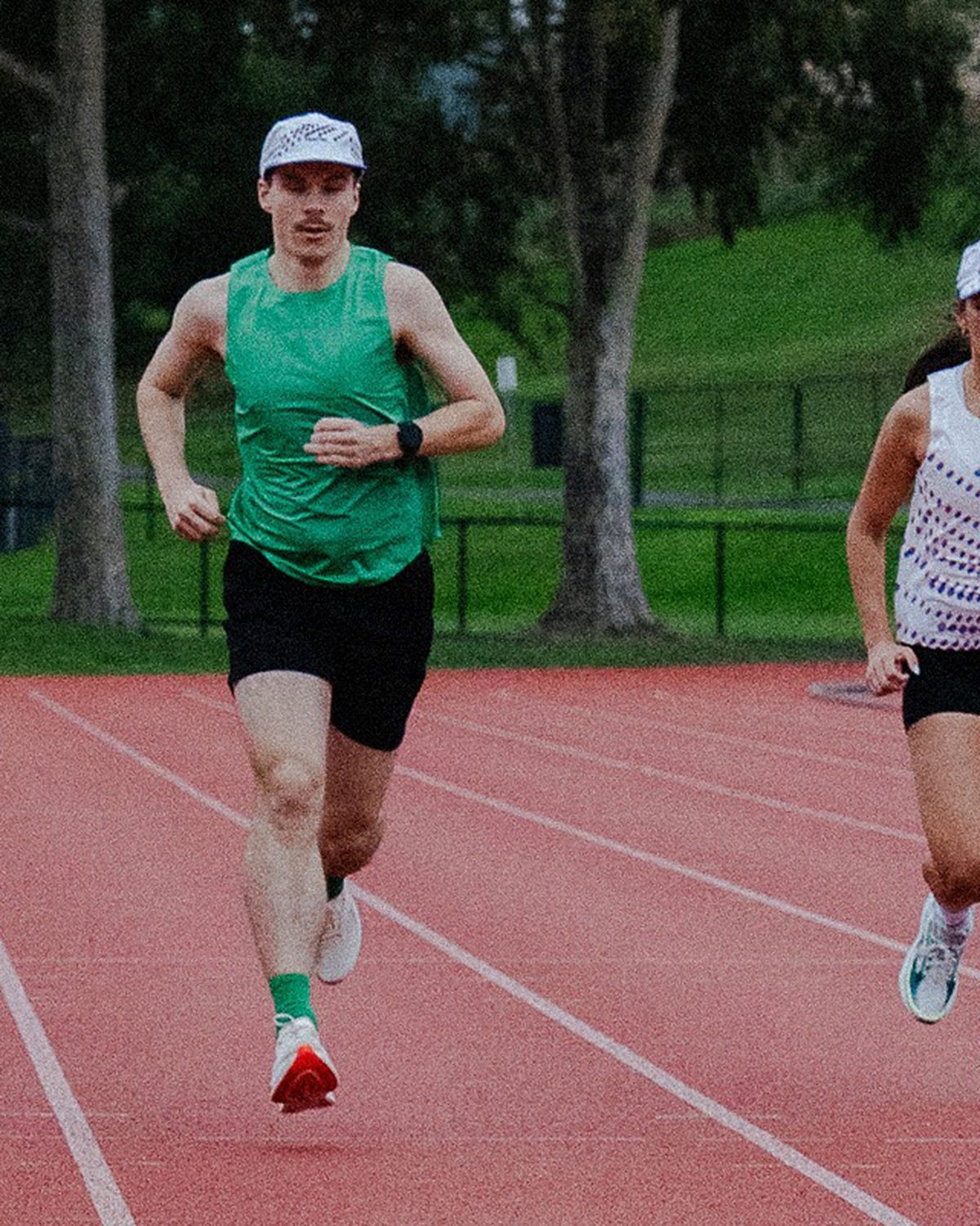 Velocity 3.0 running apparel in green, orange and white on a red track