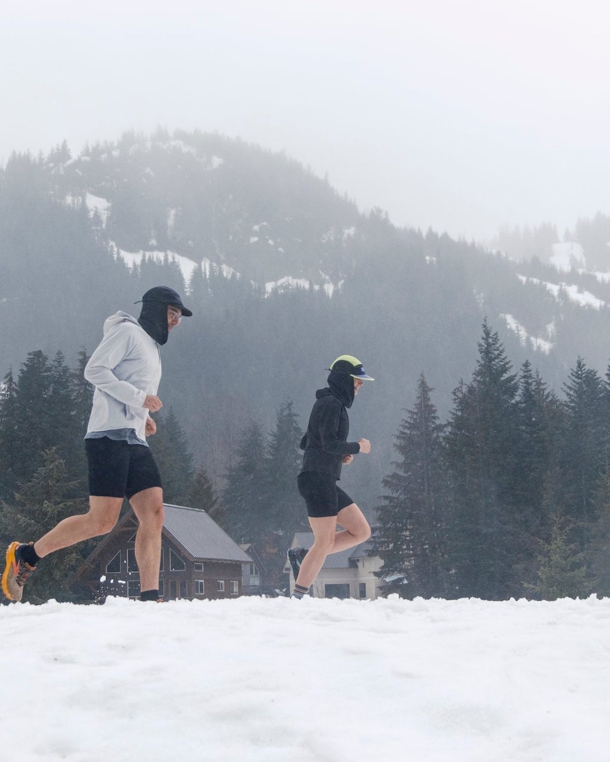 Winter running gear: runners in caps and jackets on snowy ground